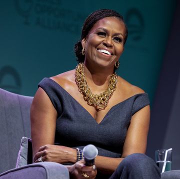 michelle obama in a blue jumpsuit and gold jewelry